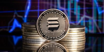 Solana SOL cryptocurrency physical coin and blurry price charts.